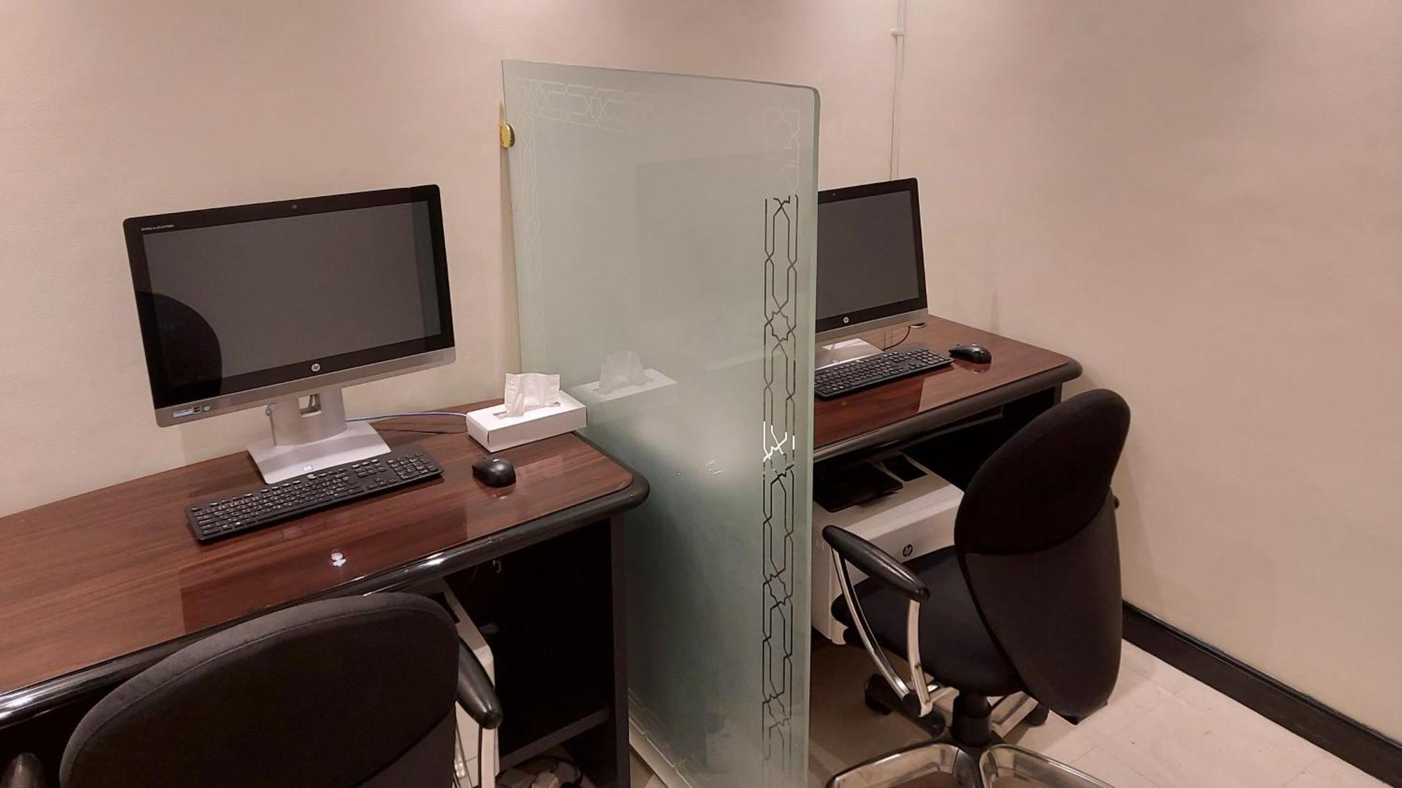 다르 알 이만 인터컨티넨탈 호텔 메디나 외부 사진 The photo shows a small workspace or office area with two computer desks. Each desk is equipped with a monitor, keyboard, and mouse. A frosted glass partition separates the two workstations, providing some level of privacy. The chairs are ergonomic a