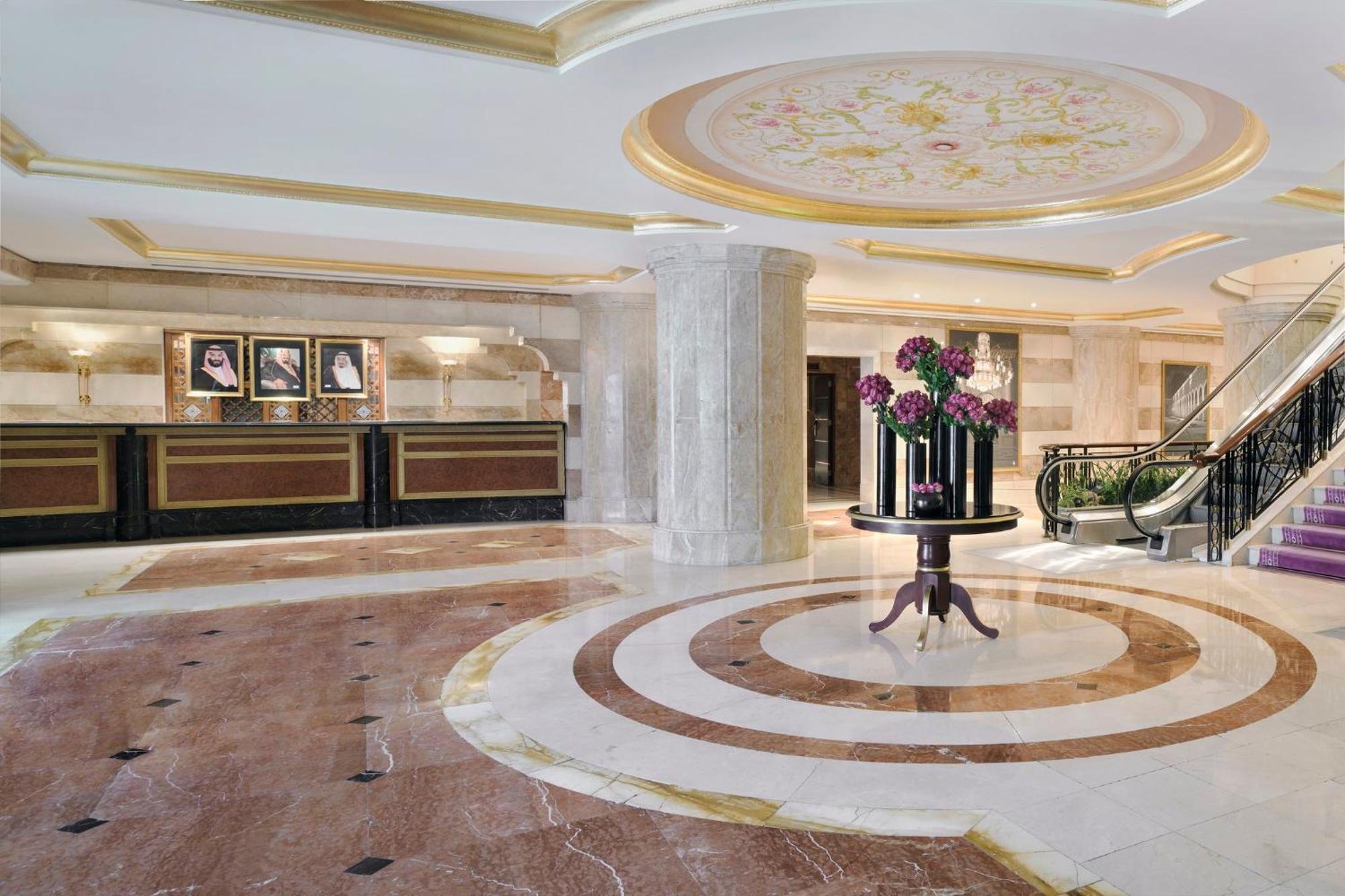 다르 알 이만 인터컨티넨탈 호텔 메디나 외부 사진 The photo shows a luxurious hotel lobby. The space features elegant marble flooring with circular designs, complemented by a large, decorative ceiling. In the center, there is a round table adorned with a floral arrangement. Behind the table, a recep